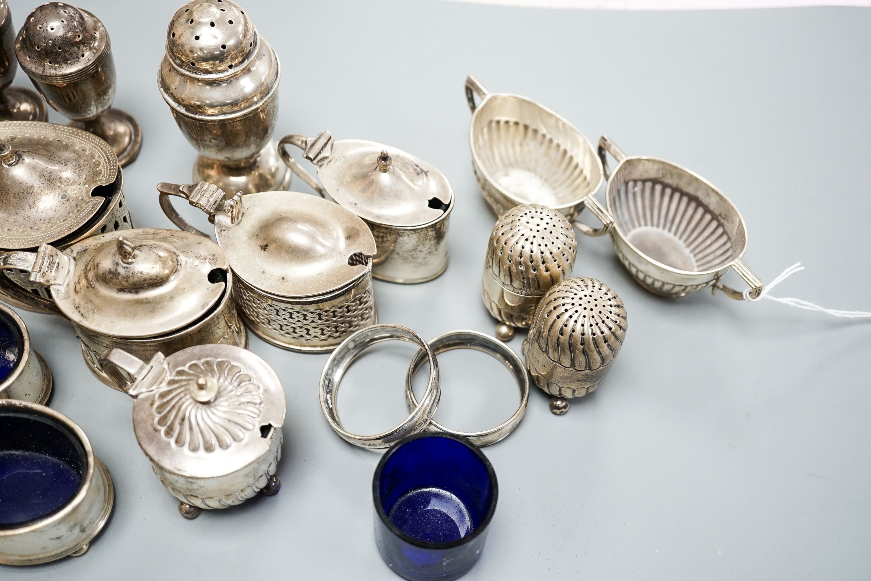 A mixed group of assorted mainly early 20th century silver condiments, including mustard pots, salts and pepperettes, two napkin rings and four plated salts, some lacking liners.